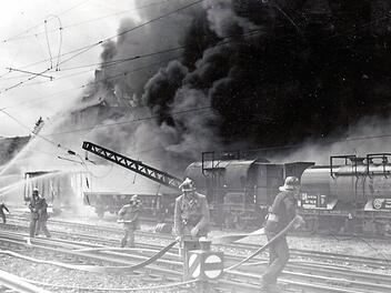 Innerhalb weniger Minuten glich am 10. Juni 1954 das Mineralölwerk Voitländer in Kronach, an der Bahnstrecke München-Berlin gelegen, einem Inferno. Durch die ungeheure Hitze bog sich ein Hochspannungsmast für die elektrische Oberleitung (linke Bildseite).  Repro: Gerd Fleischmann