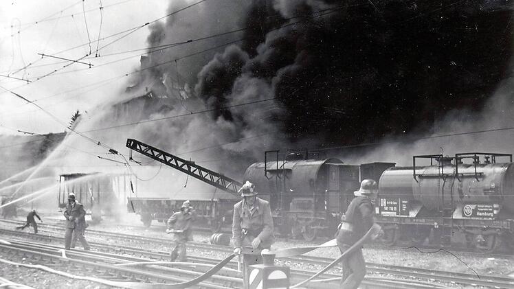 Innerhalb weniger Minuten glich am 10. Juni 1954 das Mineralölwerk Voitländer in Kronach, an der Bahnstrecke München-Berlin gelegen, einem Inferno. Durch die ungeheure Hitze bog sich ein Hochspannungsmast für die elektrische Oberleitung (linke Bildseite).  Repro: Gerd Fleischmann