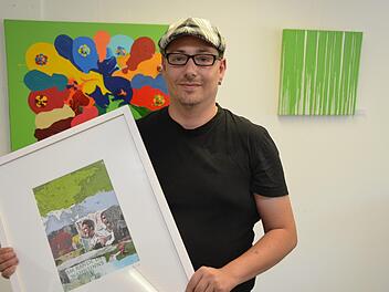 Alexander Ruppert mit einer seiner "Grünflächen", einer Collage die auf alten Landkartenblättern aufgebracht ist, dahinter ein werk von Wolfgang Feichtinger. Foto: Peter Rauch