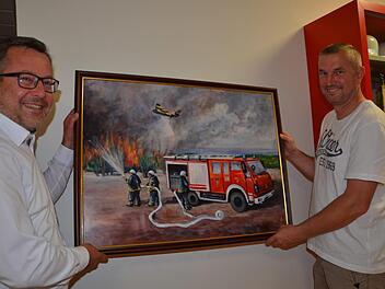 Thomas Geiger und Alexander Schöpp mit einem Gemälde, das man zum Festkommers von der Wehr aus der Partnerstadt Nova Gradiska geschenkt bekam und das das alte Herzogenauracher Löschfahrzeug bei einem Waldbrand-Einsatz in Dalmatien zeigt.  Foto: Bernhard Panzer