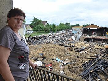 Vom Balkon des Wohnhauses hat Irmgard Schmidt vor Augen, was das Feuer von ihrem Hof übrig gelassen hat. Foto: Rainer Lutz