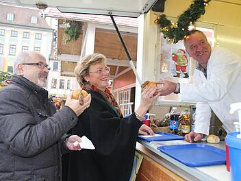 Die Europaabgeordnete Monika Hohlmeier und der Landtagsabgeordnete Jürgen W. Heike haben sich auf dem im Aufbau befindlichen Weihnachtsmarkt eine Coburger Bratwurst bestellt. Hans Brettschneider überreicht sie ihnen lachend. Foto: Helke Renner