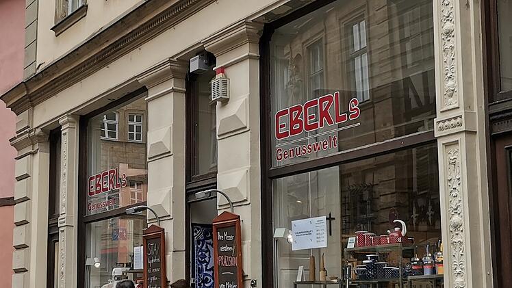 Ein Traditionsgeschäft in der Bamberger Altstadt, "EBERLs Genusswelt," steht kurz vor der Schließung. Die Fassade hat große Fenster mit dem Schriftzug des Ladens.