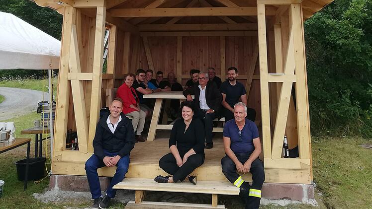 Wetterschutzhütte in Wittershausen mit Bürgermeister Mario Götz, Stephanie Kunder von der Allianz Kissinger Bogen e.V. und Ortsvorsteher und Projektkoordinator Elmar Sell, sowie auf dem Dach die beiden Zimmerer Dominik Sell und Elias Schießer. Foto: Udo Sell