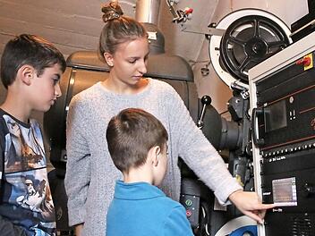 Tobias und Jakob (von links) lassen sich von Kinomitarbeiterin Lena Schneider die Technik im Vorführraum erklären. Foto: Andreas Lösch