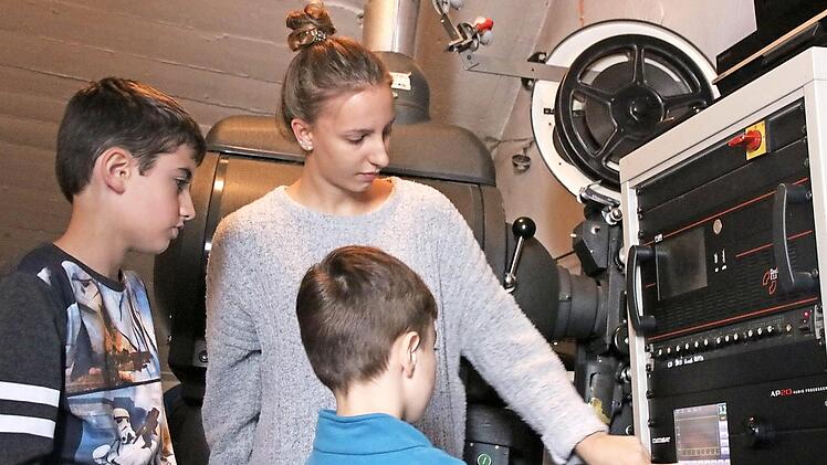 Tobias und Jakob (von links) lassen sich von Kinomitarbeiterin Lena Schneider die Technik im Vorführraum erklären. Foto: Andreas Lösch