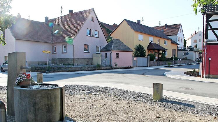 Auf dem Dorfplatz plätschert der neue Brunnen.