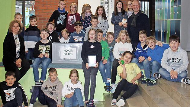Gemeinsam mit Schulleiterin Annette Marx nahm die 3. Klasse stellvertretend f&uuml;r alle Sch&uuml;lerinnen und Sch&uuml;ler die AOK-Fit-Box entgegen.