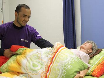 Ali Sharifi deckt im Proberaum der Altepflegeschule eine Puppe zu - während seine Klassenkameraden bereits praktisch in Altenheimen arbeiten. Wegen einer Formalität darf Sharifi seine Ausbildung derzeit nicht weiterführen. Ob er überhaupt bleiben kann, ist ungewiss. Foto: Markus Klein