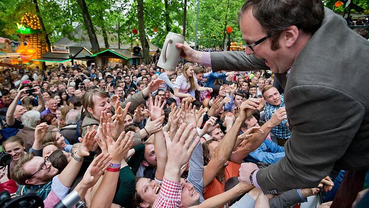 Der Erlanger Oberbürgermeister Florian Janik (SPD) verteilt am 12.05.2016 in Erlangen (Bayern) beim traditionellen Fassbieranstich der 261. Bergkirchweih Freibier. An den zwölf Festtagen bis zum 23. Mai erwartet die Stadt rund eine Million Besucher auf dem Burgberg. Foto: Daniel Karmann/dpa
