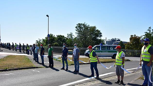 ZF-Beschäftigte bilden eine Menschenkette zwischen den Werken Süd und Nord - mit Maske und weißen Abstandshaltern. Sie fordern Klarheit über angekündigte Stellenabbaupläne. Foto: Anand Anders