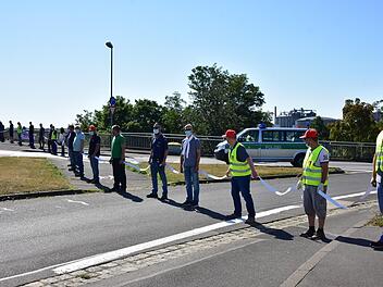 ZF-Beschäftigte bilden eine Menschenkette zwischen den Werken Süd und Nord - mit Maske und weißen Abstandshaltern. Sie fordern Klarheit über angekündigte Stellenabbaupläne. Foto: Anand Anders