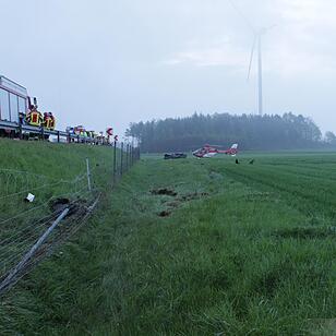 Starkregen sorgt für Abflug: Nissan schießt von Autobahn und landet drei Meter tiefer im Graben - Wagen überschlägt sich auf einer Strecke von 120 Metern mehrfach – Nissan bleibt völlig deformiert auf Wiese liegen – Fahrer eingeklemmt und schwerst verletzt – Polizei sucht nach Unfallzeugen