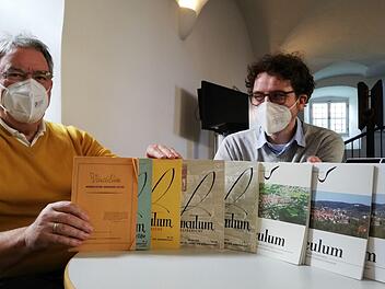 Paul Ziegler von den Studiengenossen (links) und Nicolas Zenzen zeigen eine Auswahl des Vinculum aus sieben Jahrzehnten. Die erste Ausgabe links im Bild war noch lediglich als kleiner Rundbrief gedacht.