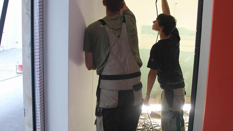 Peter Bechstein und Kevin Schulz (rechts) bauen eine Tür ein.