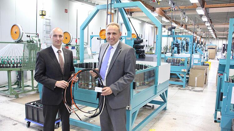 Delfingen-Juniorchef Gérald Streit (links) und Geschäftsführer Matthias Littig mit einigen durch textile Flechtsysteme geschützten Kabeln vor einer der Flechtmaschinen in Marktrodach  Fotos: Friedwald Schedel