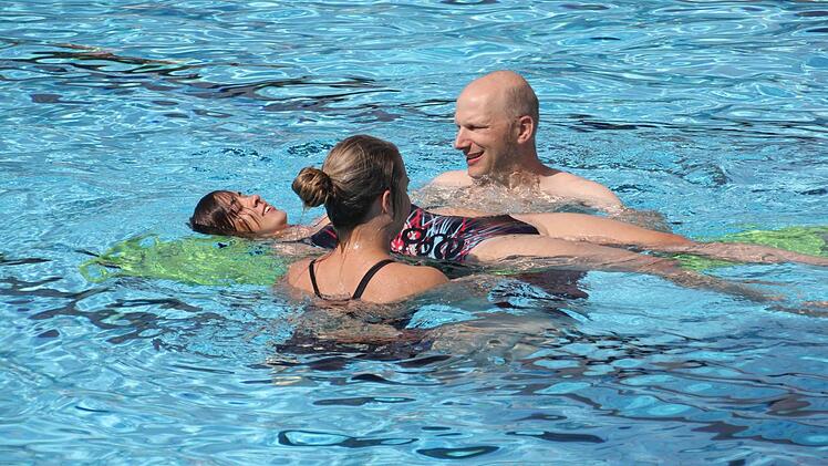 Stefan, Sandra und Eva von der DLRG-Ortsgruppe Ebern demonstrieren das Retten einer Person mit Lagerung auf einer Transportschiene, um so leichter längere Strecken kräfteschonend bewältigen zu können.