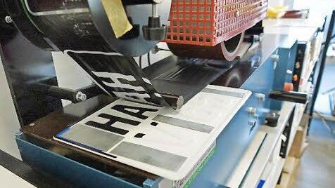 Die Maschine überzieht die gestanzten Buchstaben mit einer Farbfolie.