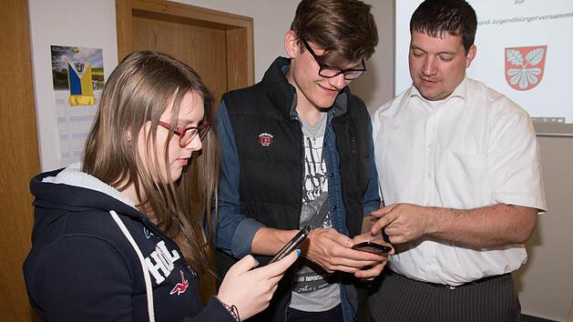 Mit ein wenig Hilfe von Bürgermeister Peter Kraus (rechts) konnten Ina-Sofie Müller und Jonas Erickson (von links) die App der Gemeinde Gädheim auf ihr Smartphone laden.