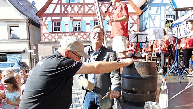 Bürgermeister Heinz Richter schwingt den Holzhammer zum Bieranstich - ein Helfer hält das Fass.  Fotos:  Petra Malbrich