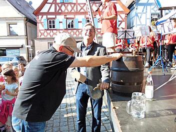 Bürgermeister Heinz Richter schwingt den Holzhammer zum Bieranstich - ein Helfer hält das Fass.  Fotos:  Petra Malbrich