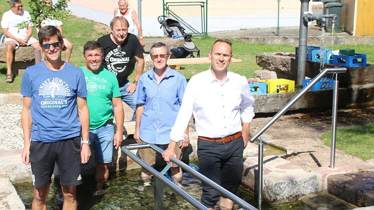 Das Wasser kommt aus einer circa einen Kilometer entfernten Quelle Richtung Hassenbach und hat konstante zwölf Grad Celsius. Zum Wassertreten ideal. Dies testen Bürgermeister Mario Götz, Oliver Schlereth, Herbert Schmitt, Christoph Kleinhenz und Paul Bieber.  Foto: Hilmar Ruppert