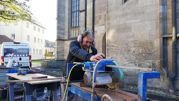 Karl Sperling schneidet auf dem Kirchplatz Bodenplatten in die richtige Größe. Foto: Heike Beudert