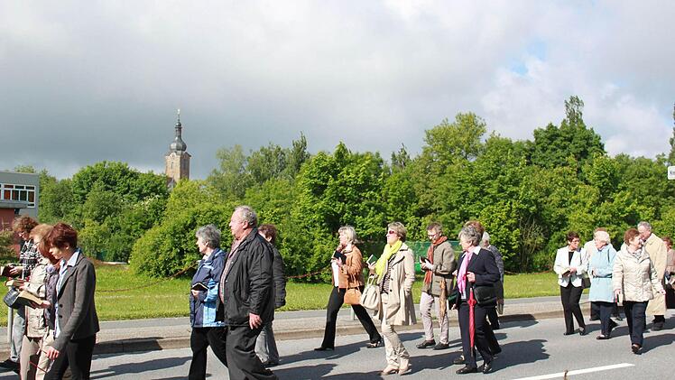 Im Hintergrund über der Stadtpfarrkirche sind bereits die dunklen Wolken, doch die Prozession läuft im Sonnenschein. Foto: Katharina Brecht