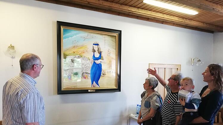 George Charbonnier erklärt Pater Markus Reis (links) seine Interpretation der  österlichen Szene mit seiner Figur der Maria Magdalena im Zentrum des Bildes. Auch seine Frau Christiane und Elisabeth Mehler mit Charbonniers Enkel Arthur  auf dem Arm hören ihm zu.Foto: Heike Beudert