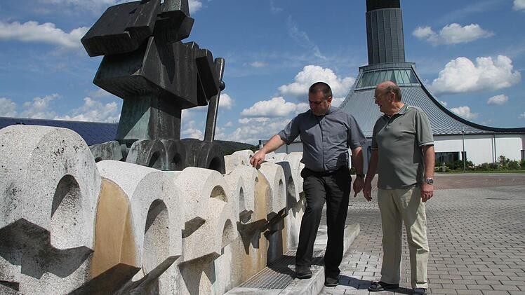 Die hässlichen braunen Flecken am Christophorusbrunnen vor der Autobahnkirche Himmelkron sind vermutlich Kalkablagerungen. Der Brunnen, der erst zehn Jahre alt ist, soll nun saniert werden, sind sich Pfarrer Michal Osak (links) und Kirchenpfleger Hartmut Richter einig. Foto: Jürgen Gärtner