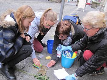Victoria Renger, Jasmin Parys, Maria del Carmen Schmucker-Brabec und Hanne Plentz (von links) schrubben in der Judengasse die Stolpersteine von Hermann Wolf und Frieda Baumwollspinner, die einst dort gewohnt hatten. Foto: Martin Koch