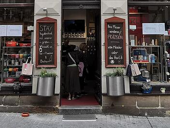 Ein traditionsreiches Geschäft in der Bamberger Altstadt schließt bald. Schaufenster mit Küchenartikeln und Schildern, die auf Verkaufsangebote hinweisen. Kunden betreten den Laden.