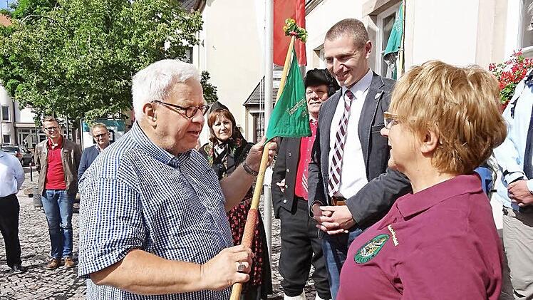 Wimpelübergabe durch den Rhönklubpräsidenten Jürgen Reinhardt (links) an Gersfelds Zweigvereinsvorsitzende Margit Trittin (rechts). Gersfelds Bürgermeister Steffen Korell (Mitte) freute sich, das der Gründungsort Gersfeld für die 140. Hauptversammlung Gastgeber sein darf.  Foto: Eckert