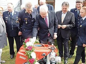 Bürgermeister Harald Hübner (vorne) startet die neue Tragkraftspritze.