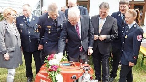 Bürgermeister Harald Hübner (vorne) startet die neue Tragkraftspritze.