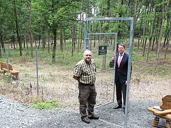 Der naturbelassene Tierfriedhof im Callenberger Forst ist mit Bänken für die Tierbesitzer ausgestattet und jederzeit zugänglich. Der Zaun sei allerdings Vorschrift, um Wildtiere fernzuhalten, wie Prinz Hubertus (rechts) und Revierleiter Christoph Schiesser erläuterten. Foto: Ulrike Nauer