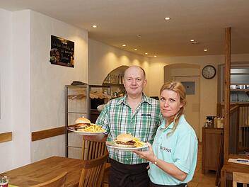 Inhaber Bodo Schmidt und Mitarbeiterin Tatjana Stoll servieren zwei Burger.Foto: Arkadius Guzy