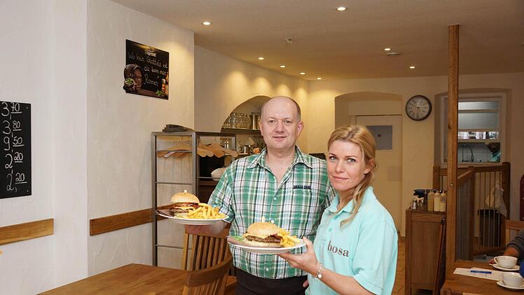 Inhaber Bodo Schmidt und Mitarbeiterin Tatjana Stoll servieren zwei Burger.Foto: Arkadius Guzy