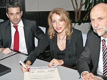 Sanny van Heteren, mit Kurdirektor Frank Oette und Oberbürgermeister Kay Blankenburg, unterzeichnet die Urkunde, die sie zur Botschafterin von Bad Kissingen ernennt. Foto: Werner Vogel