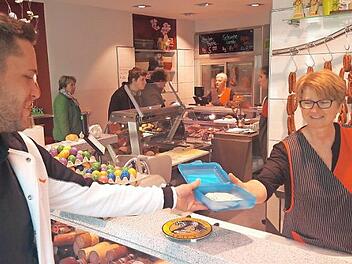 Petra Schonath händigt einem Kunden die Wurst in dessen Mehrwegbox aus.  Foto: Bernhard Panzer