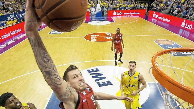 Daniel Theis schlie&szlig;t per Dunking ab. Die Oldenburger Frantz Massenat (l.) und Jan Niklas Wimberg befinden sich in der Zuschauerrolle.  Foto: Ulf Duda