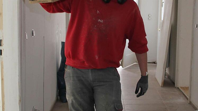 Lucas Budemann schleppt den Fußbodenbelag ins Pfarrhaus.