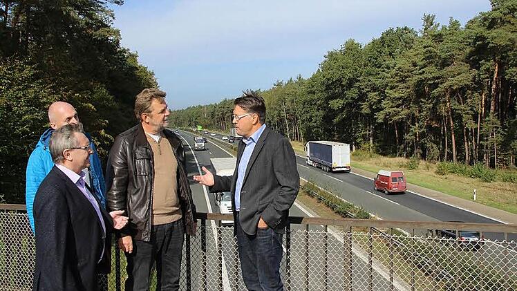 Die Bürgermeister Karsten Fischkal und Horst Rehder und ihre Mitarbeiter Martin Hofmann und Peter Müller (von rechts) sind nicht begeistert, dass in dem Wald im Hintergrund etwa 900 Meter von Klebheim entfernt ein größerer Autobahnparkplatz entstehen soll.  Foto: Andreas Dorsch