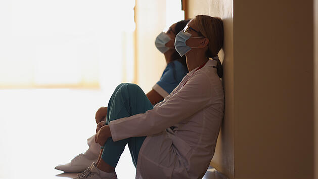 Erschöpfte Krankenschwestern nach harter, langer Operation auf dem Boden im Flur sitzend, schwierige Schicht, Schichtarbeit, Nachtschicht