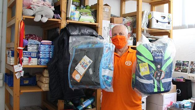 Wolfgang Speyer nimmt zwei Schultaschen aus dem Regal, um  zu zeigen, wof&uuml;r  Spendengelder verwendet werden. Foto: Charlotte Wittnebel-Schmitz