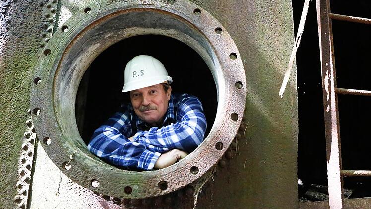 Richard Schmitt ist stolzer Besitzer eines 15 Hektar großen Gelände mitten im Wald bei Ebrach. Mehrere riesige Tanks sind dort versteckt. Der Tank, aus dem Schmitt auf dem Bild blickt, ist allerdings nicht mehr in Gebrauch. Foto: Matthias Hoch