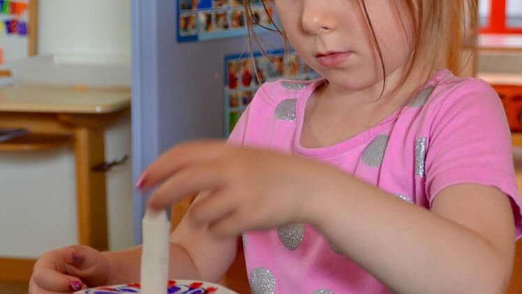 Malina hat einen Kreis aus Filterpapier geschnitten und bemalt. Mit Hilfe eines gerollten Zewa-Papieres wird das Wasser aus dem Glas auf das Papier geleitet. Die Malerei verschwindet daraufhin und die Farben verschmelzen. Foto: Kathrin Kupka-Hahn
