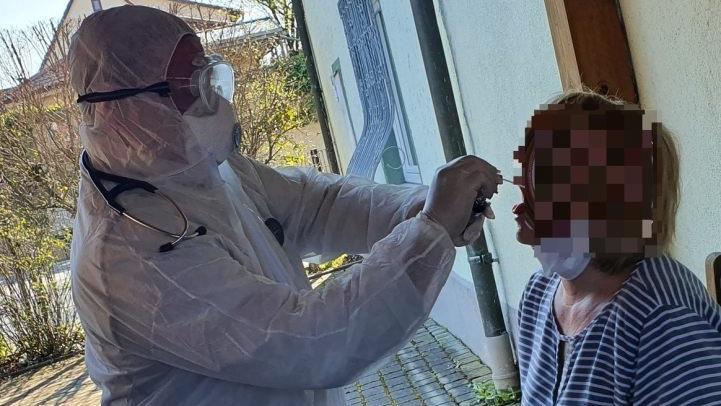 Der Weismainer Arzt Christopher Kirsten nimmt im Hof seiner Praxis einen Abstrich bei einer Patientin vor - in voller Schutzmontur.  Foto: privat