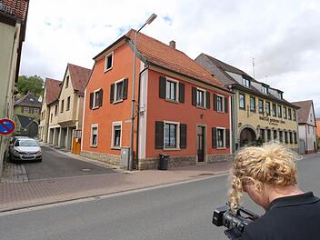 Ein Kameramann steht vor einer Gasse in Mainstockheim. In der Gasse befindet sich eine Asylbewerberunterkunft, die nach Streitigkeiten mit Anwohnern geräumt wurde. Foto: Karl-Josef Hildenbrand/dpa