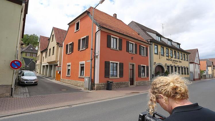 Ein Kameramann steht vor einer Gasse in Mainstockheim. In der Gasse befindet sich eine Asylbewerberunterkunft, die nach Streitigkeiten mit Anwohnern geräumt wurde. Foto: Karl-Josef Hildenbrand/dpa